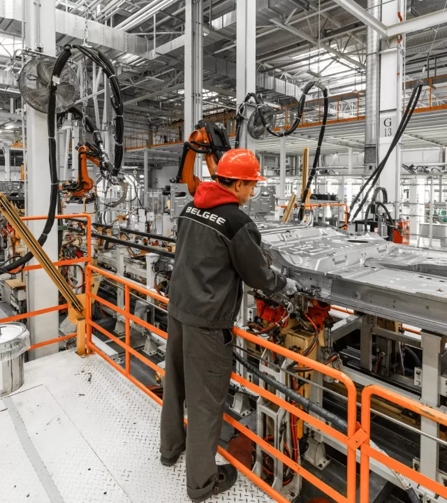 photo-automobile-production-Assembly-Lines-welding-car-body-modern-car-assembly-plant-auto-industry-male-worker-orange-protective-helmet-scaled